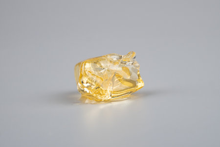 yellow piece cannabis resin concentrate on gray background. high thc diamond.