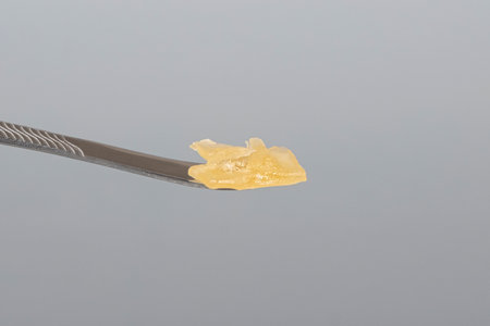 cannabis resin wax and dab tool for smoking close up on gray background.