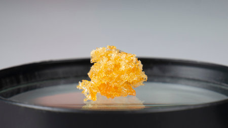 golden crystals of cannabis wax, glass container with crumbs of marijuana concentrate and copy space.の写真素材