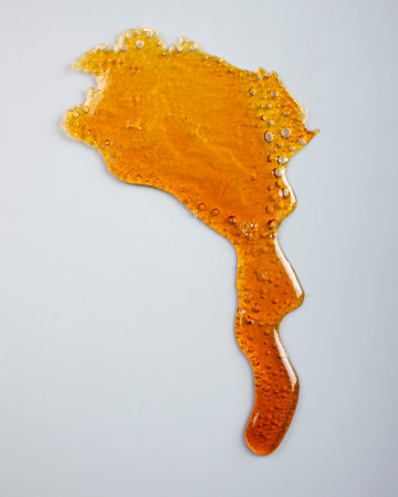 amber cannabis resin on gray background, thc wax rosin.の写真素材