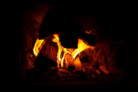burning firewood in the oven closeup, cozy warmth by the fireplace.