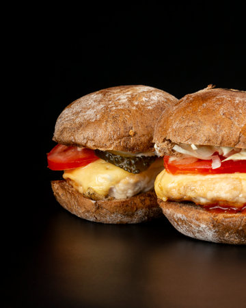 2 juicy burgers with vegetables and a large chicken cutlet in dark background ,fast food cheeseburgers.の写真素材