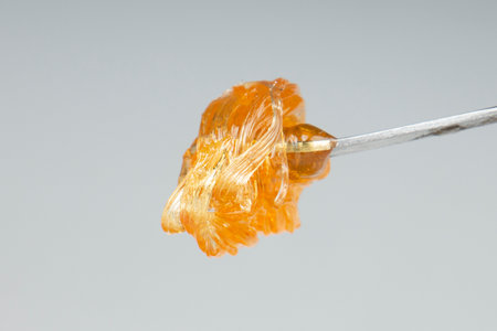 yellow gold cannabis extract wax concentrate dripping from the dabbing tool closeup.の写真素材