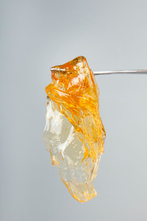 yellow gold cannabis extract wax concentrate dripping from the dabbing tool closeup.の写真素材