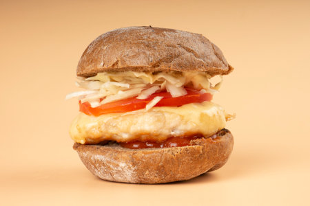 burger with vegetables and juicy bun on a beige background closeup.の写真素材