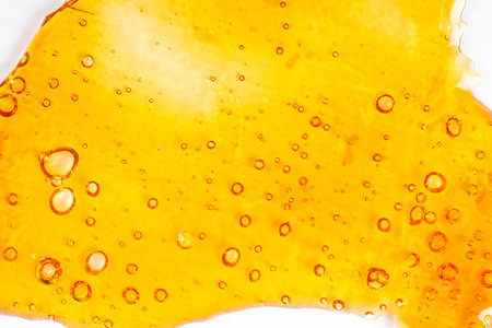 strong extract of gold cannabis wax with high thc close up, bubble shatter texture on paper.の写真素材