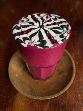 Healthy dragon fruit milkshake with a chocolate swirl pattern three quarter close up view on distressed wood surface.の写真素材