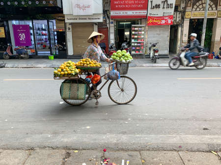 Hanoi, Vietnam - November 15,2019 : Asian woman walking bike, fruit vendorのeditorial素材