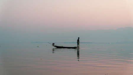 Nyaungshwe, Myanmar : March 12, 2020 - Fisherman fishes with net Inle Lake, second largest, at sunrise. silhouette at golden hourのeditorial素材