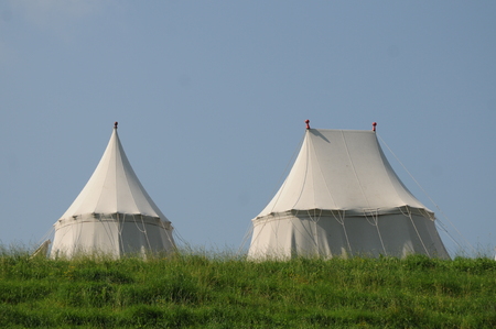 These are medieval tents on a green field in summer. They are built in the historical way the tents were during the medieval ages in Europe.の写真素材