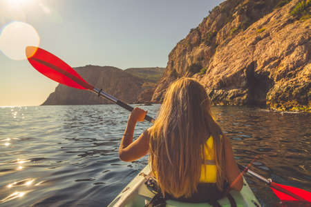Young woman kayaking in the sea near mountainsの写真素材