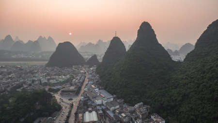Breathtaking aerial view over beautiful karst mountain landscape and Li River covered with haze or fog at sunset in Yangshuo County, China.の写真素材
