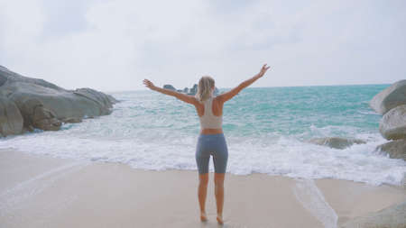 Athletic woman jogging along the beach, feeling happy and anxious to see the ocean. Happiness, success, energy and active healthy lifestyle concept.の写真素材