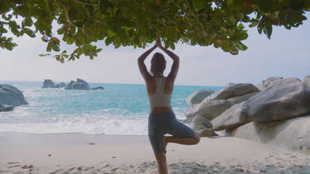 Yoga woman practices yoga and meditates in lotus position on beach sea. Healthy female girl sits in pose of lotus sukhasna meditating or practicing yoga in nature ocean outdoors, relaxingの写真素材