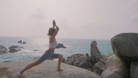Yoga woman practices yoga and meditates in lotus position on beach sea. Healthy female girl sits in pose of lotus sukhasna meditating or practicing yoga in nature ocean outdoors, relaxingの写真素材