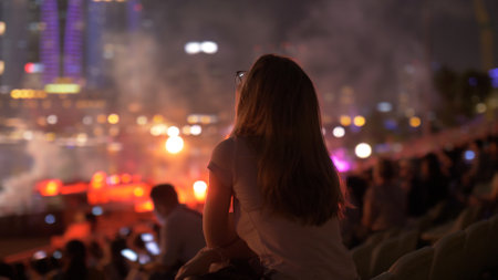 silhouette of young blonde female at a concert in front of the scene in bright light with fire show outdoors. Night scene. Leisure activity, entertainment industry concept.の写真素材
