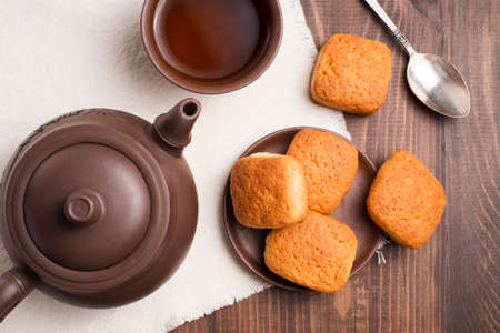 Square mug of tea with shortbread biscuits, on a brown table and a napkinの写真素材
