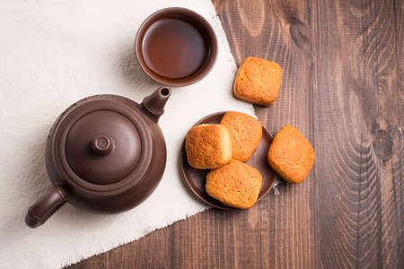 Square mug of tea with shortbread biscuits, on a brown table and a napkinの写真素材