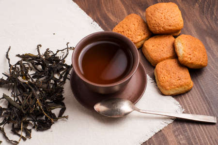 Square mug of tea with shortbread biscuits, on a brown table and a napkinの写真素材