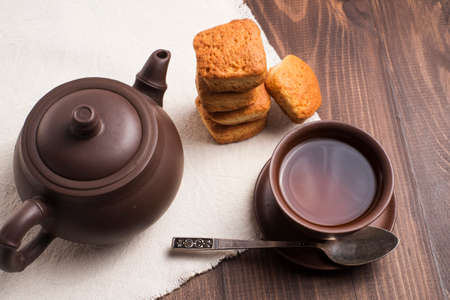Square mug of tea with shortbread biscuits, on a brown table and a napkinの写真素材