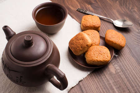 Square mug of tea with shortbread biscuits, on a brown table and a napkinの写真素材