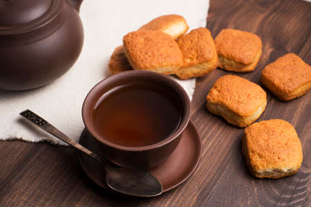 Square mug of tea with shortbread biscuits, on a brown table and a napkinの写真素材
