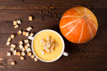 Cream soup of pumpkin with spices, with cream, crackers, on a brown wooden tableの写真素材