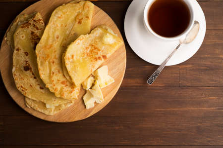 Vegetarian tortilla with potatoes and butter. Decorated tea set laid out on a wooden Board and brown tableの写真素材