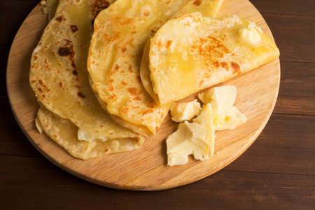 Vegetarian tortilla with potatoes and butter. Laid out on a wooden Board and brown tableの写真素材