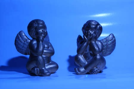 Two angels are relaxing on their clouds in the sky. の写真素材