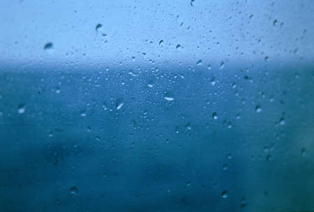 Drops on the window and the background blue sea