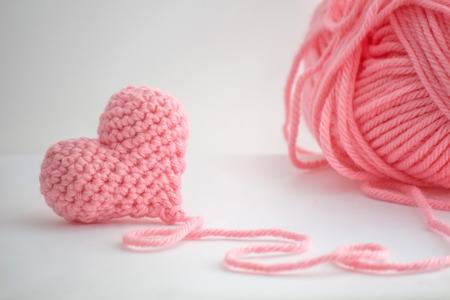 Adorable little heart crocheted by hand. Made with a thread of a thick bulky wool thread. The thread is not cut and still attached to the heart.の写真素材