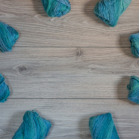 Many yarns balls on a wooden background arranged in a circle shapeの写真素材