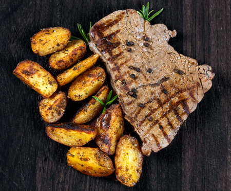 Grilled Beef Steak with Baked on Grill village potatoes, rosemary on wooden old board.の写真素材