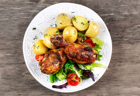 Baked chicken legs with potatoes and vegetables.の写真素材