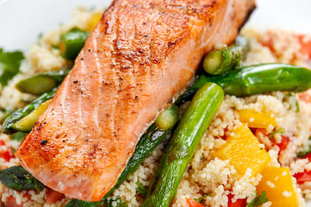 Pan fried salmon with tender asparagus and courgette served on couscous mixed with sweet tomato, yellow pepper salsaの写真素材