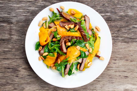 Fresh Tasty Mango, beef salad with vegetables and nuts. on wooden background.の写真素材