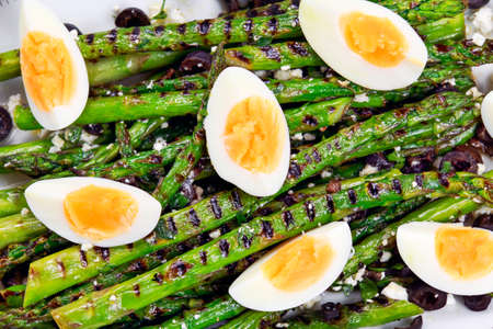 Grilled asparagus salad with feta cheese, olives and eggs.の写真素材