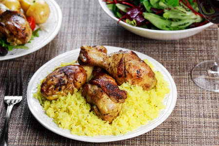 Baked chicken legs with yellow rice on table.の写真素材