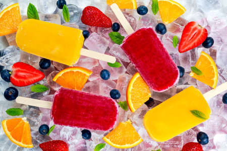 refreshing fruit ice cream lollies on ice background with berries and peppermint.の写真素材