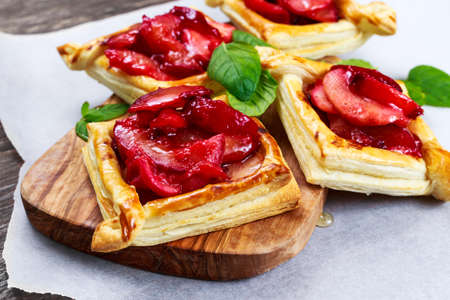 Puff pastry pies with plums, apples, mint and honey.の写真素材