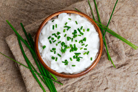 Cottage cheese with chives in wooden bowl. background.の写真素材