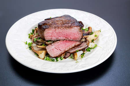 Tasty Beef Mignon sliced steak with mushrooms and herbs on plateの写真素材