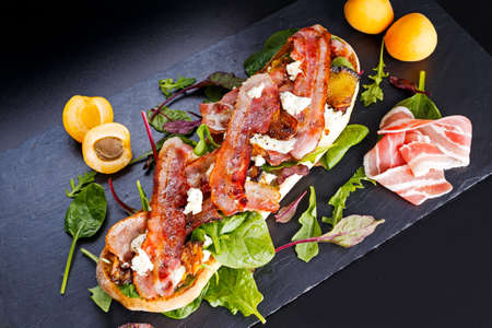 Grilled summer chiabatta with caramelized apricots, bacon, mozzarella and green salad.の写真素材