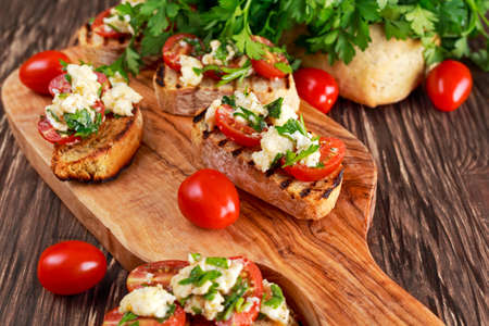 grilled appetizer bruschettas with red grape tomatoes, mozzarella and parsley sprinkle.の写真素材