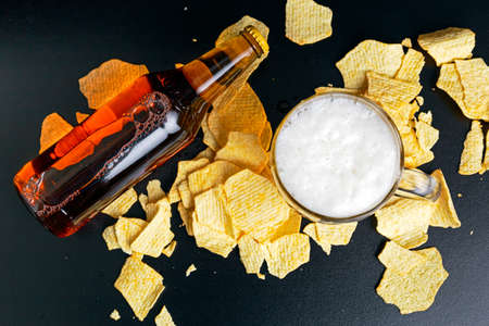 Mug Beer with potato chips on black background.の写真素材
