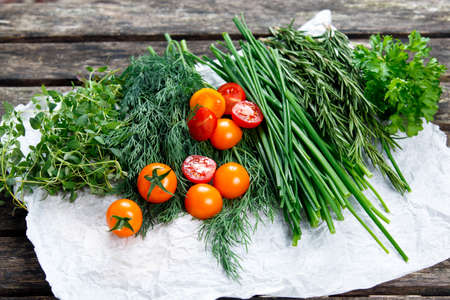 Fresh Tomatoes and Green Vegetables. Onion, Dill, Rosemary, Parsley, Chives and thyme. on old wooden tableの写真素材