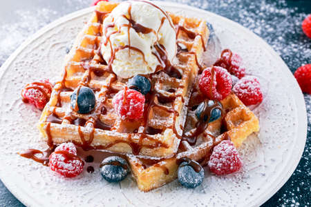 Plate of waffles with ice cream, chocolate sauce and fresh berries.の写真素材