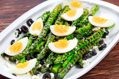 Grilled asparagus salad with feta cheese, olives and eggs.の写真素材