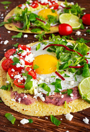Huevos Rancheros Breakfast tostadas with avocado, feta cheese and vegetablesの写真素材